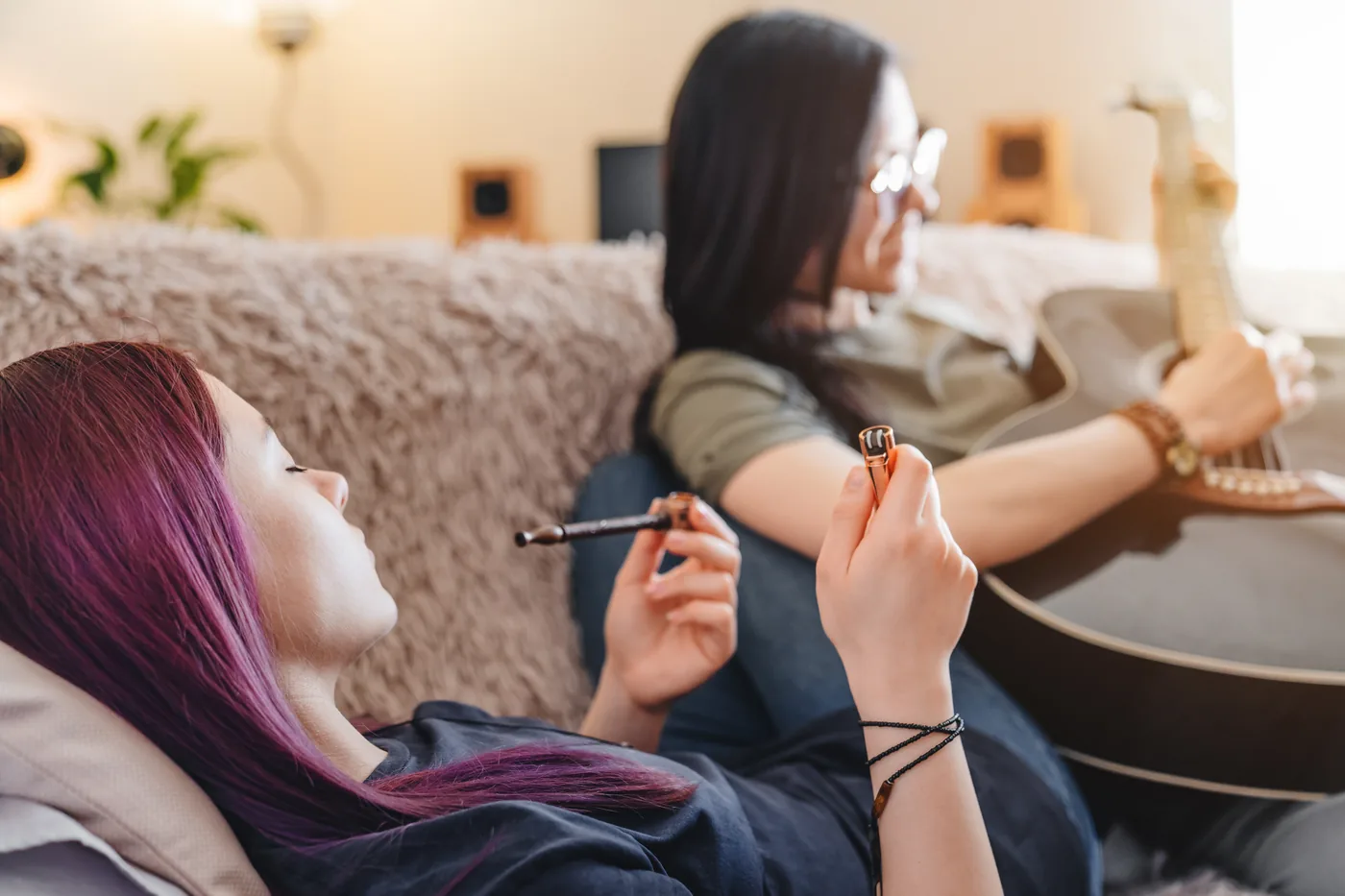 Two friends relaxing on a couch with a guitar